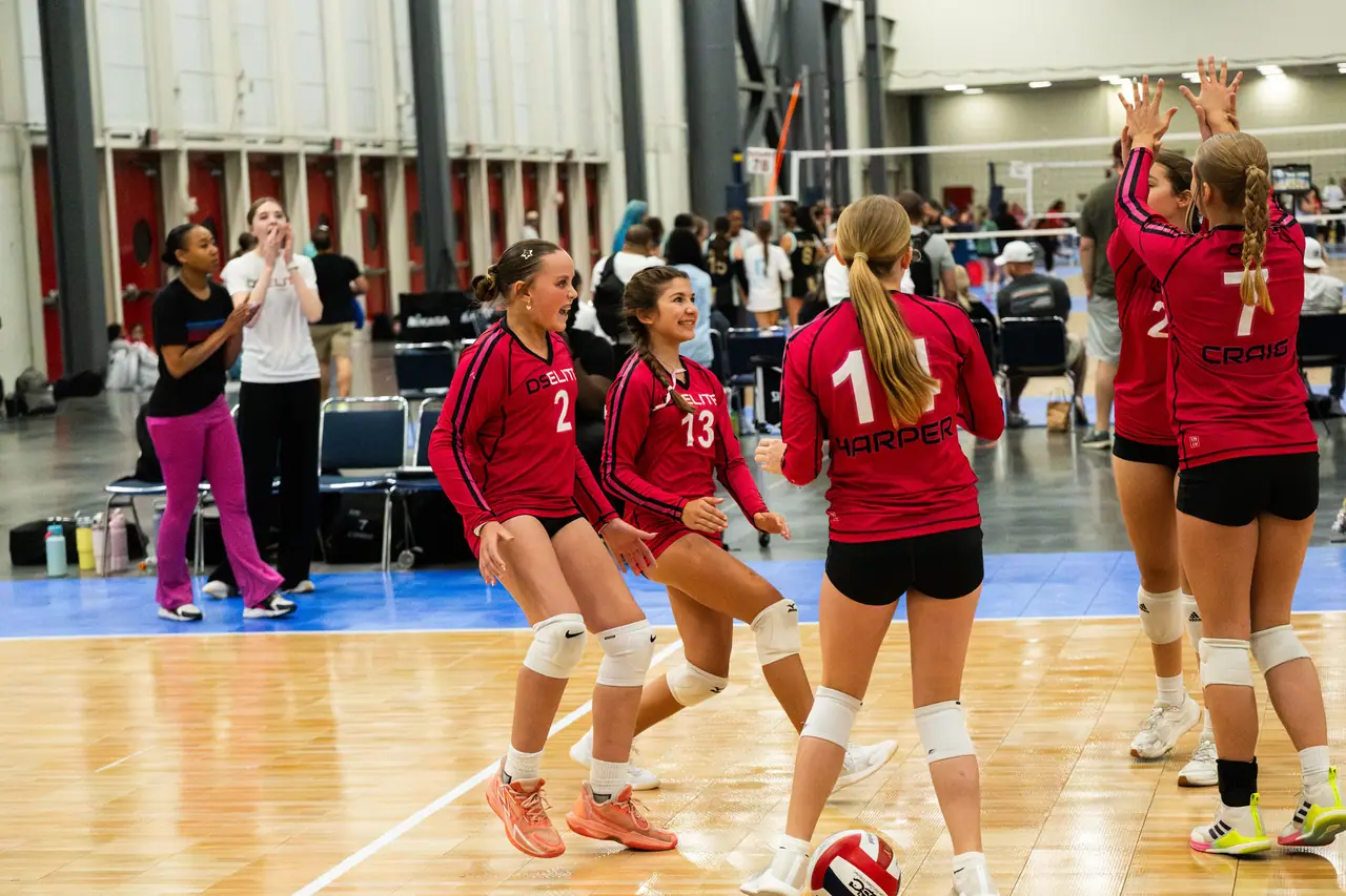 DS Elite players in red uniforms grinning and trading high fives after a point